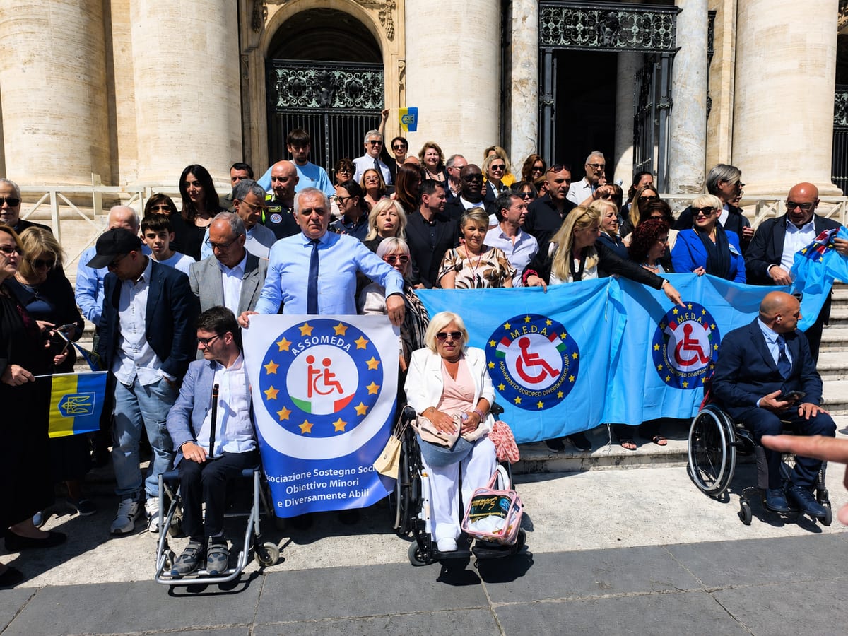 Soci e volontari di ASSOMEDA APS con lo striscione dell'associazione durante un evento istituzionale