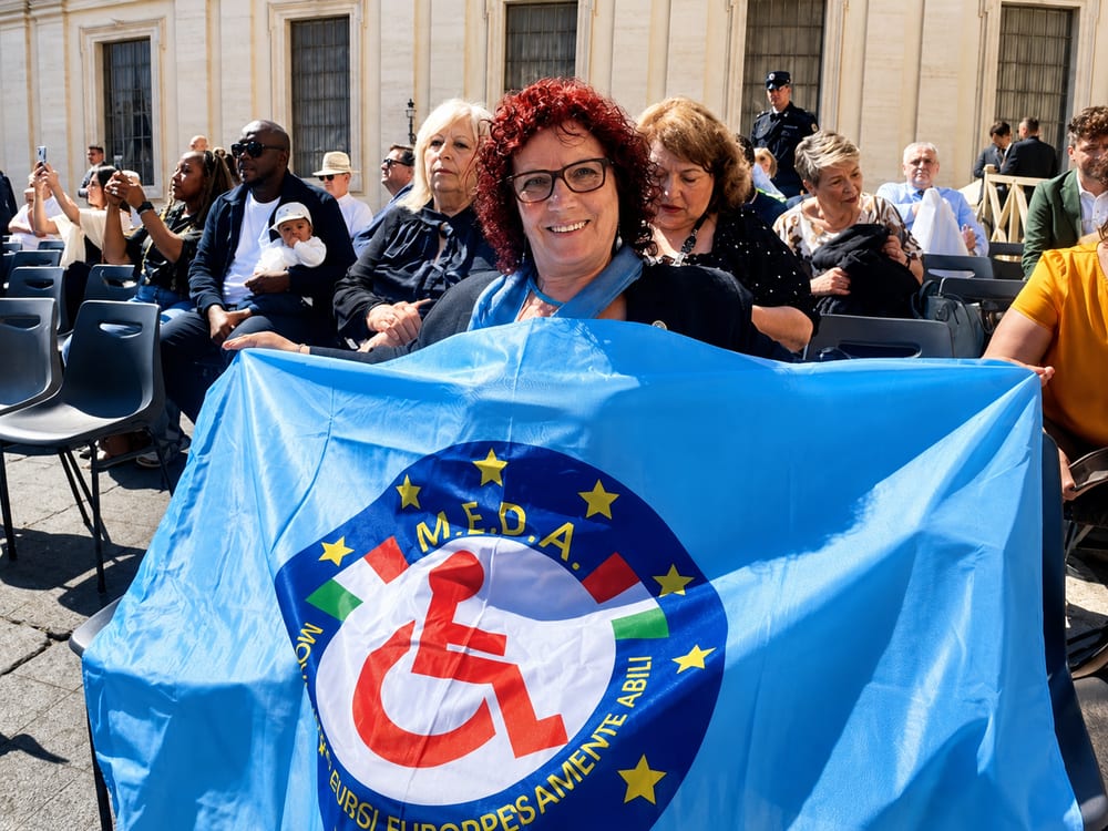 Una volontaria sorridente mostra la bandiera dell'associazione durante un evento